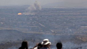 Israelis and tourists look at fire caused by fighting in Syria from an observation point on Mt. Bental in the Golan Heights, near the border between the Golan Heights and Syria, Friday, June 7, 2013. Syrian rebels on Thursday briefly captured a crossing point along a cease-fire line with Israel in the contested Golan Heights. (AP Photo/Sebastian Scheiner)
