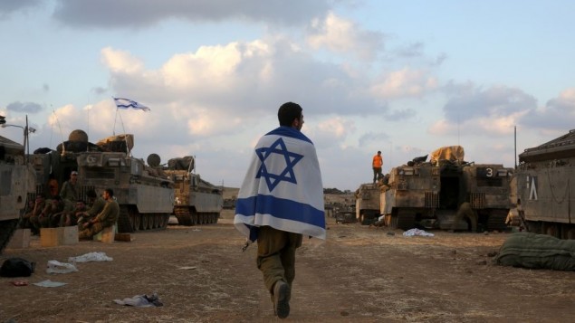 Un soldat israÃ©lien porte le drapeau israÃ©lien Ã  Gaza - 19 juillet 2014 (CrÃ©dit : Nati Shohat/Flash90)