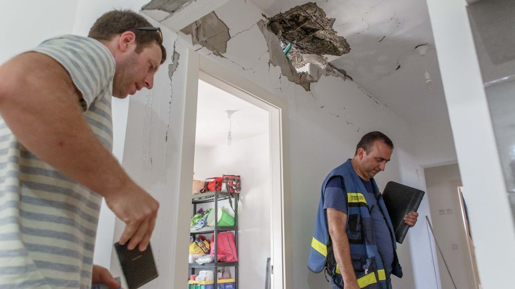 Tax authority workers survey the damage caused to a house after it was hit by a rocket in the Ashkelon Regional Council, on August 20, 2014. (photo credit: Flash90) Tax authority workers survey the damage caused to a house after it was hit by a rocket in the Ashkelon Regional Council, on August 20, 2014. (photo credit: Flash90)