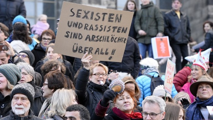 A woman holds up a sign reading "Sexists and racists are assholes-everywhere" while taking part in a demonstration against violence against women in front of the cathedral in Cologne, western Germany, on January 9, 2015 (Roberto Pfeil/AFP) A woman holds up a sign reading "Sexists and racists are assholes-everywhere" while taking part in a demonstration against violence against women in front of the cathedral in Cologne, western Germany, on January 9, 2015 (Roberto Pfeil/AFP)