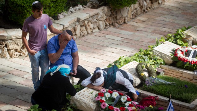 Bereaved Israelis mourn next to graves of fallen soldiers at the Mt. Herzl military cemetery in Jerusalem on Israeli Memorial Day. May 11, 2016. (Miriam Alster/Flash90)