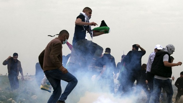 Palestinian demonstrators run as Israeli security forces fire tear gas toward them following a protest to mark Land Day in the village of Madama, south of Nablus, in the West Bank, March 30, 2017. (AFP/JAAFAR ASHTIYEH)