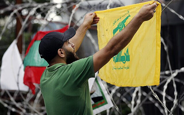 A Hezbollah supporter chants slogans as he holds his group's flag during a protest against U.S. interference in Lebanon's affairs, near the U.S. embassy in Aukar, northeast of Beirut, Lebanon, Friday, July 10, 2020. (AP Photo / Hussein Malla)