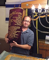 Jerry Schranz holds one of the restored Torah scrolls.